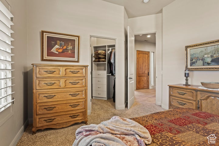 Bedroom featuring light carpet, a walk in closet, a closet, and baseboards