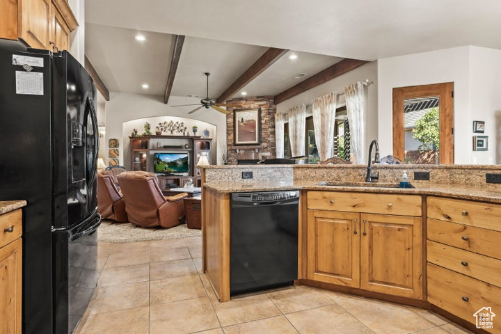 Kitchen with black appliances, open floor plan, a sink, light stone countertops, and ceiling fan