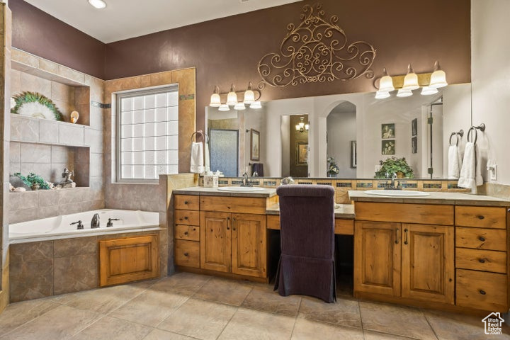 Bathroom featuring two vanities, a garden tub, and tile patterned flooring