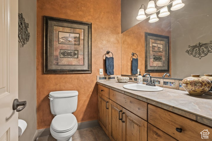 Bathroom with vanity, toilet, baseboards, and tile patterned flooring
