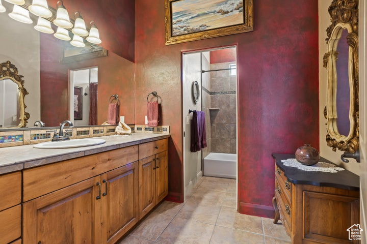 Full bathroom with vanity, tile patterned floors, shower / bath combination, and baseboards