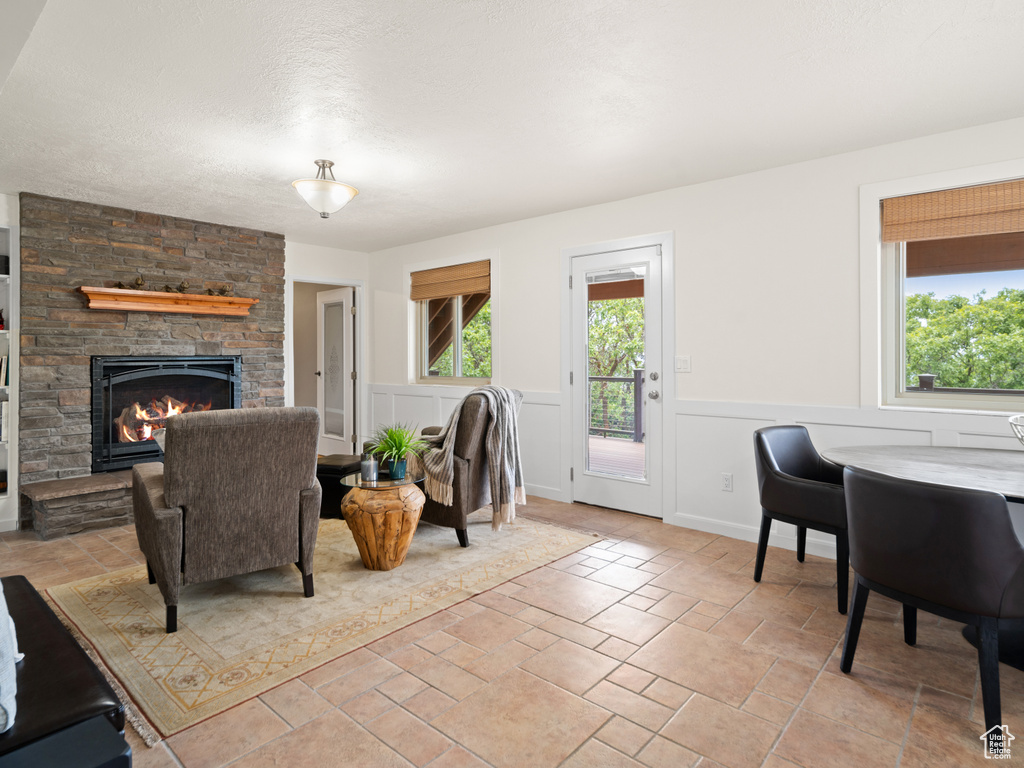 Living area featuring a fireplace, wainscoting, and light stone finish floors