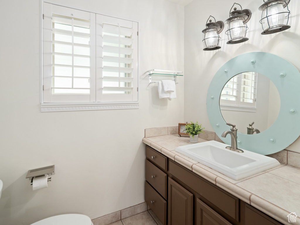 Bathroom with plenty of natural light, vanity, toilet, and tile patterned floors