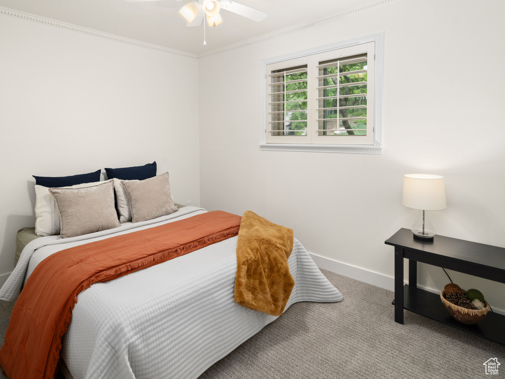 Carpeted bedroom with ornamental molding, baseboards, and ceiling fan
