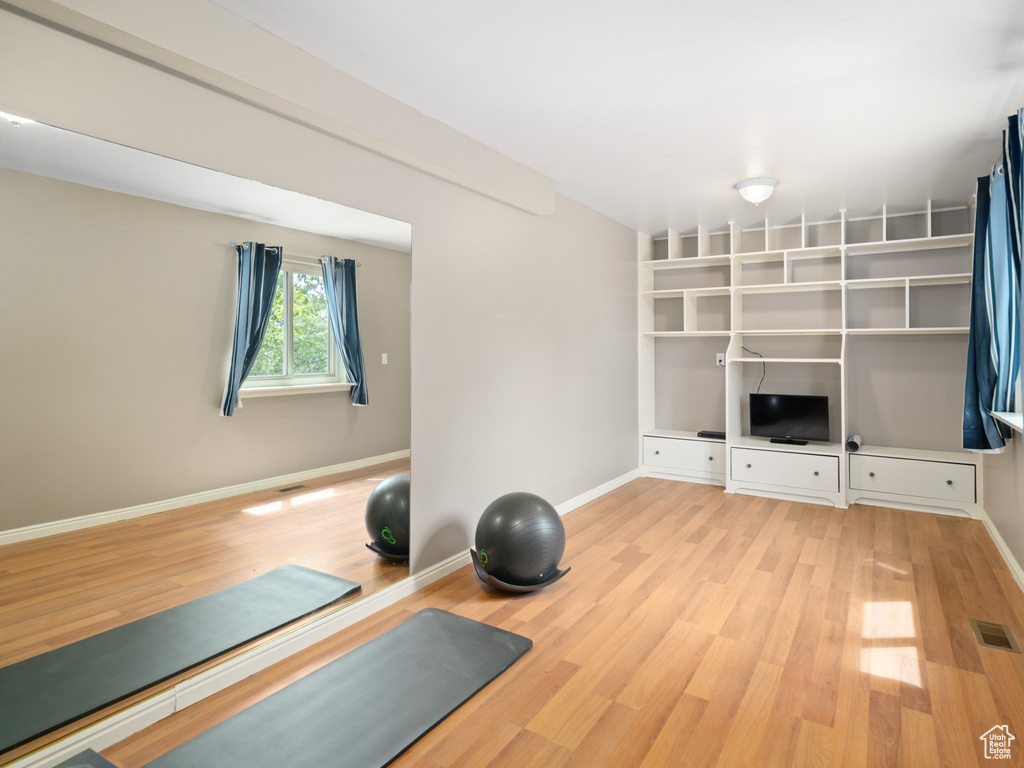 Workout room with light wood-type flooring and baseboards