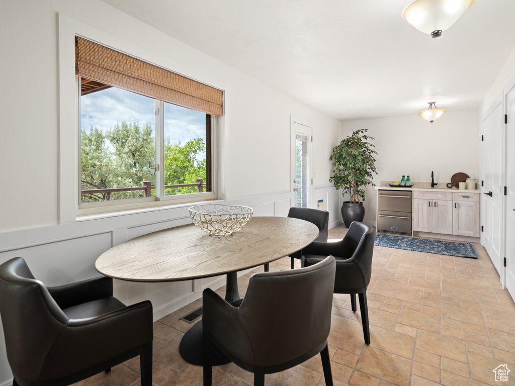 Dining room with stone tile floors, wainscoting, and a decorative wall