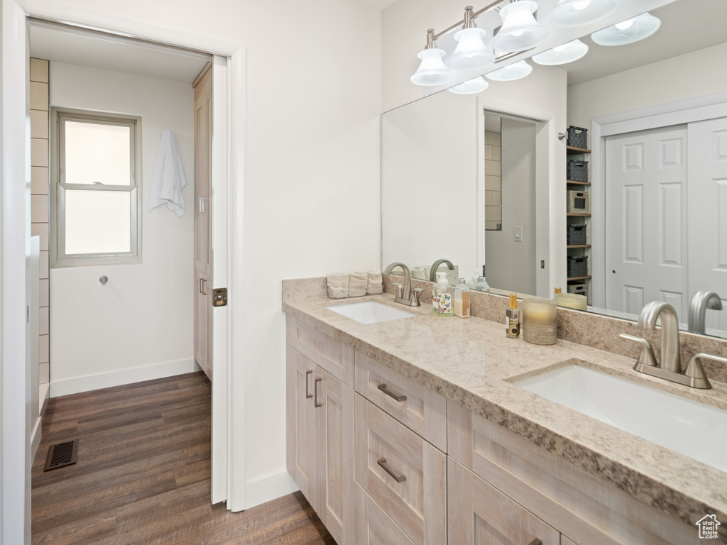 Bathroom featuring double vanity, wood finished floors, and baseboards
