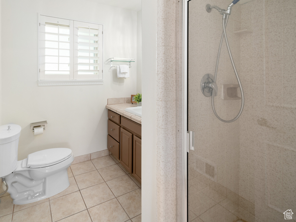 Bathroom featuring toilet, vanity, a shower stall, and tile patterned flooring