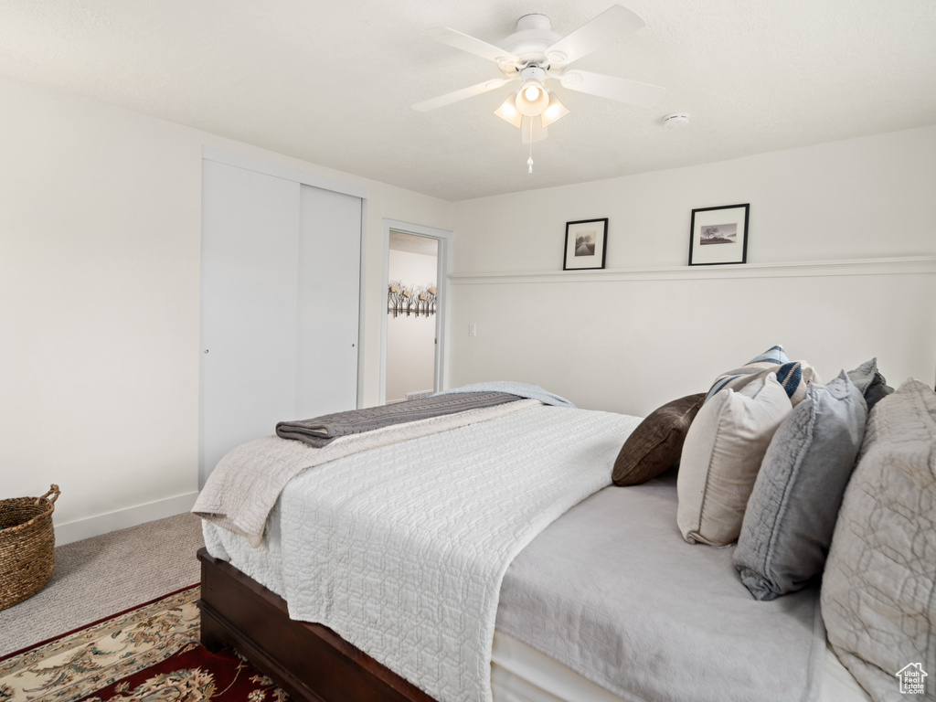 Carpeted bedroom with baseboards, a closet, and a ceiling fan