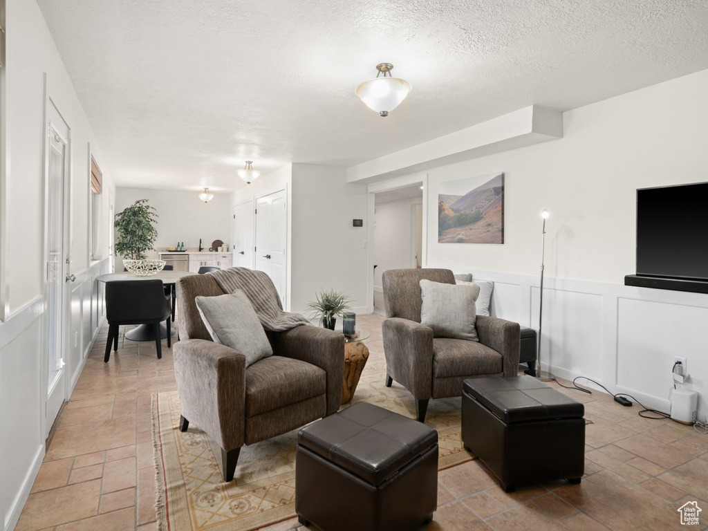 Living area featuring stone tile flooring, wainscoting, and a decorative wall