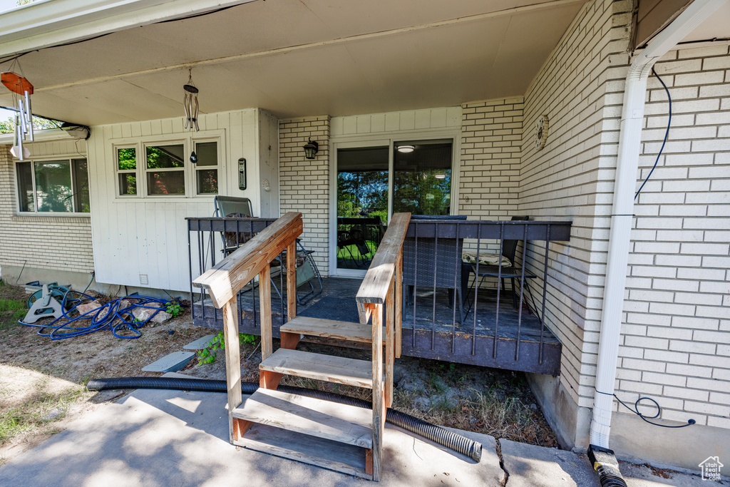 Entrance to property featuring brick siding and a wooden deck
