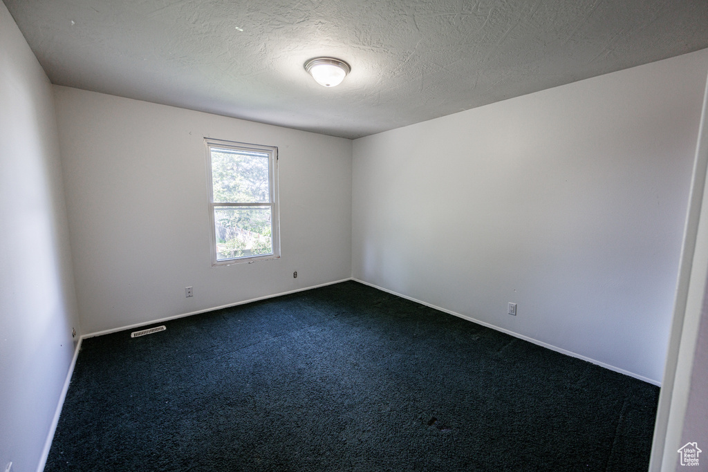 Empty room with dark carpet and baseboards