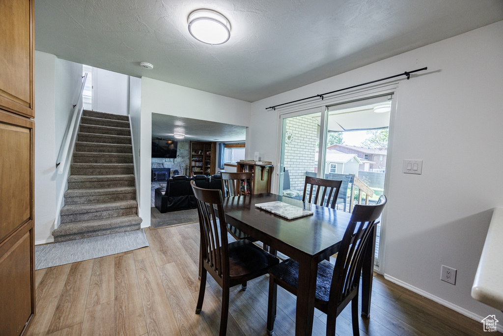 Dining room with stairs, light wood-style floors, a fireplace, and baseboards