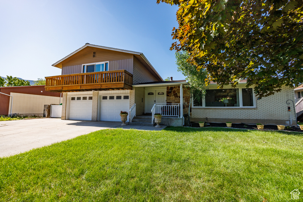 Split level home with a porch, driveway, a front lawn, and brick siding