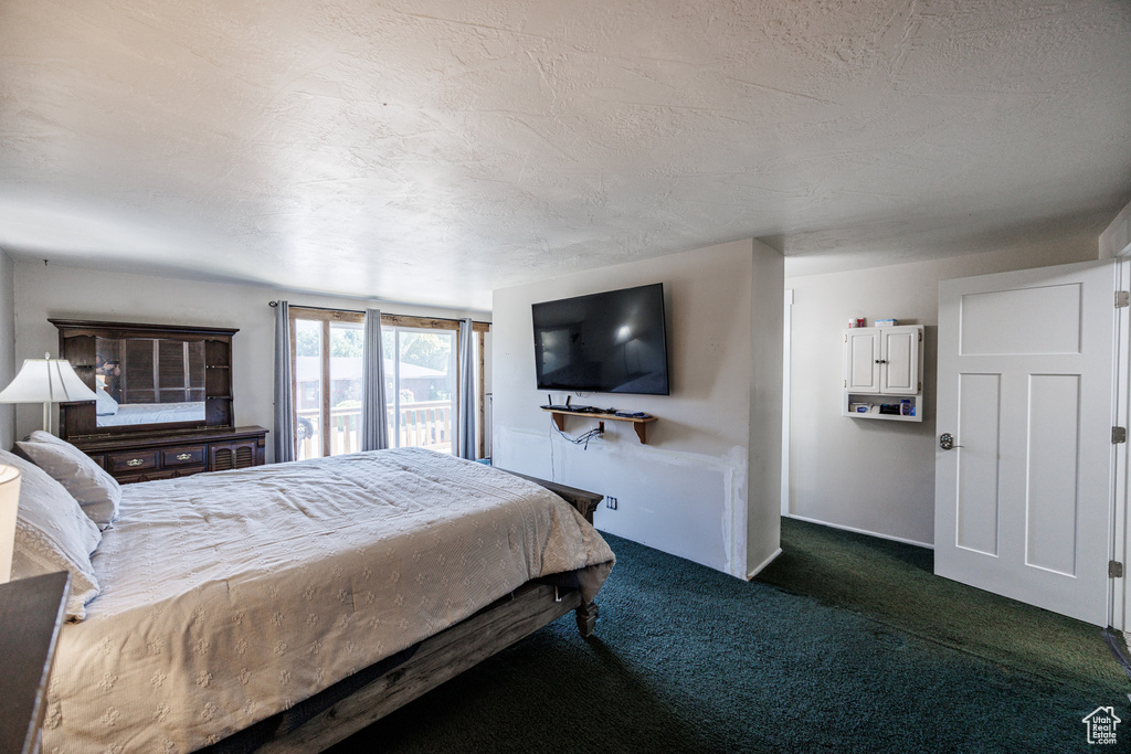 Bedroom with dark carpet, a textured ceiling, and access to outside