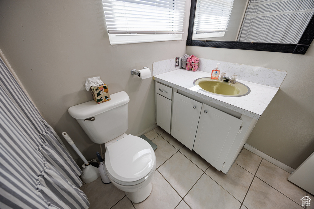 Bathroom with plenty of natural light, vanity, toilet, and tile patterned floors