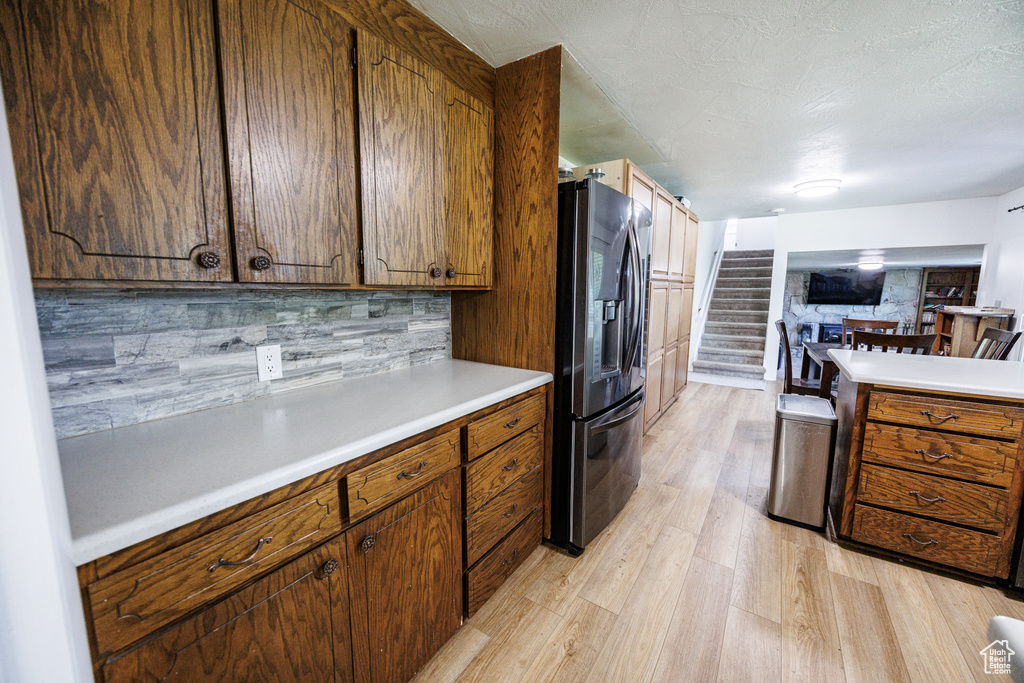 Kitchen featuring fridge with ice dispenser, light wood finished floors, light countertops, and brown cabinets