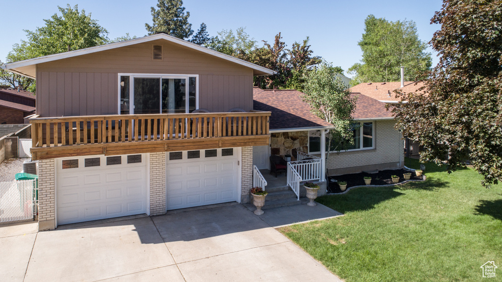 View of front of home with driveway, a front yard, an attached garage, roof with shingles, and brick siding