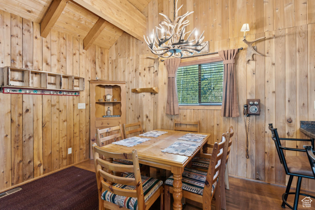 Dining area featuring wooden walls, a chandelier, wood ceiling, and wood finished floors