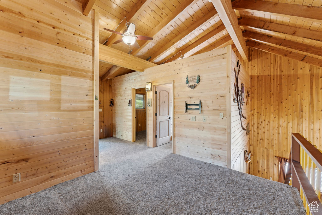 Carpeted empty room featuring wood walls, wooden ceiling, and a ceiling fan