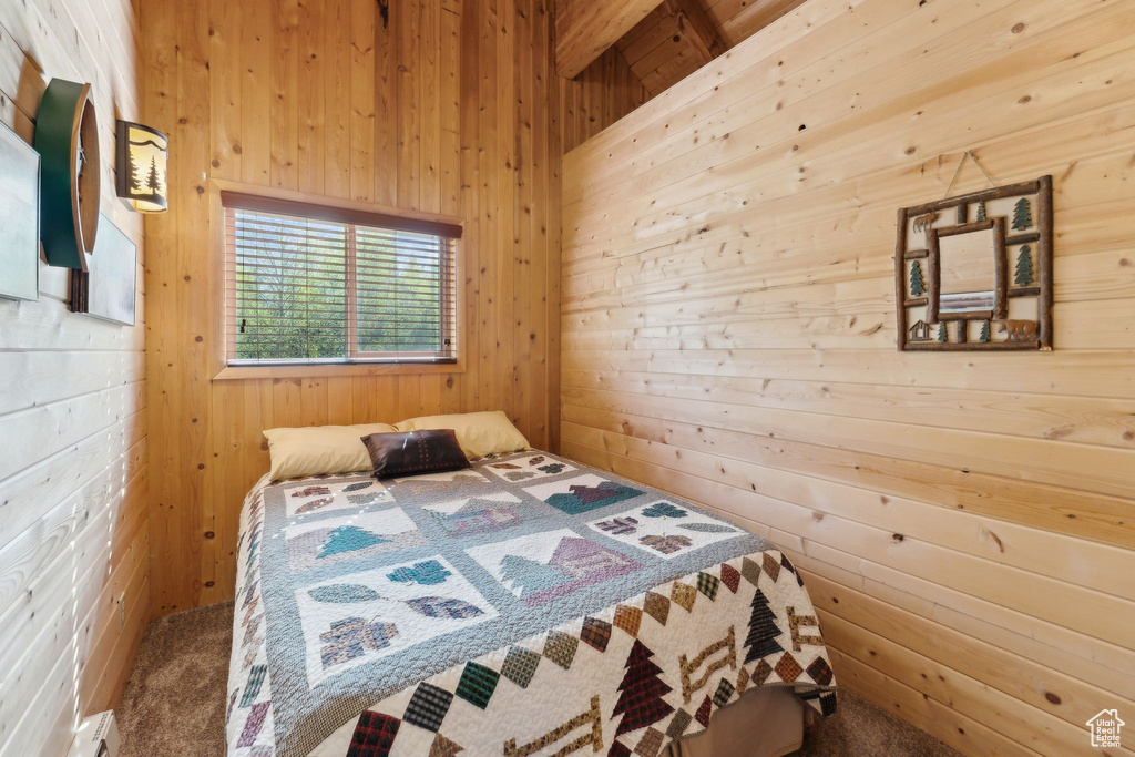 Bedroom featuring wooden walls, carpet floors, and a baseboard heating unit
