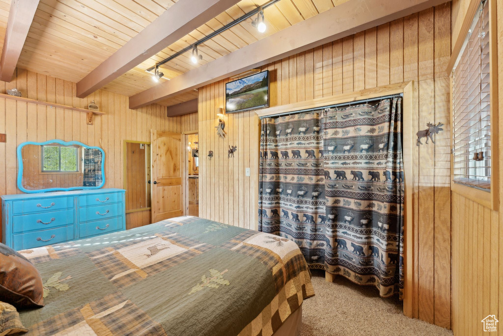 Bedroom with track lighting, wooden walls, carpet, and wood ceiling with exposed beams
