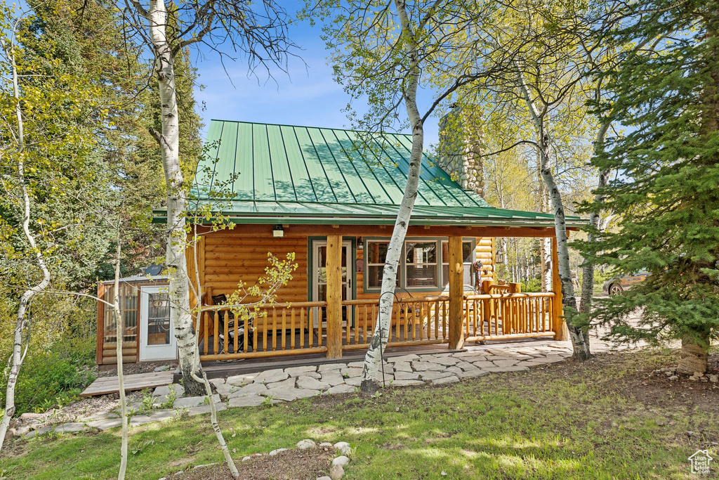 Rear view of house featuring a standing seam roof, covered porch, faux log siding, and metal roof