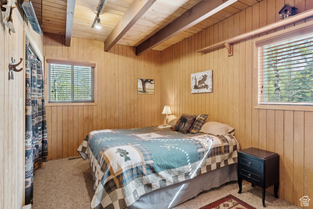 Bedroom featuring carpet flooring, wooden ceiling with exposed beams, and wooden walls