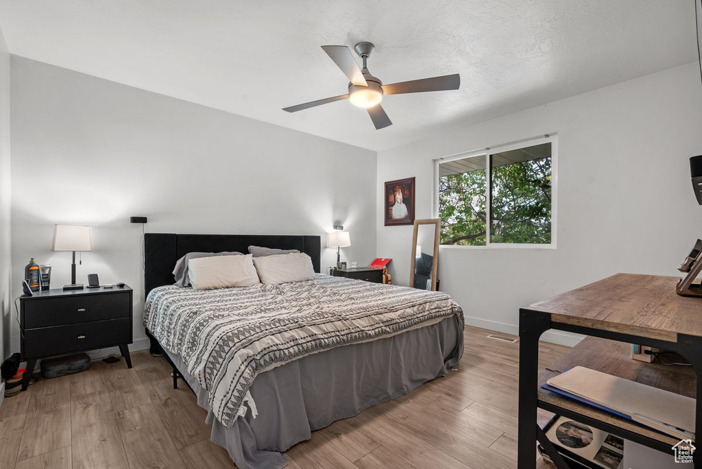 Bedroom featuring light wood-style flooring, baseboards, and a ceiling fan
