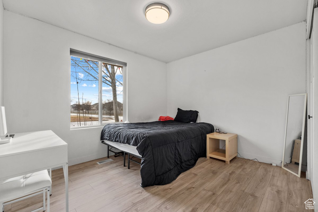 Bedroom featuring multiple windows, light wood finished floors, and baseboards