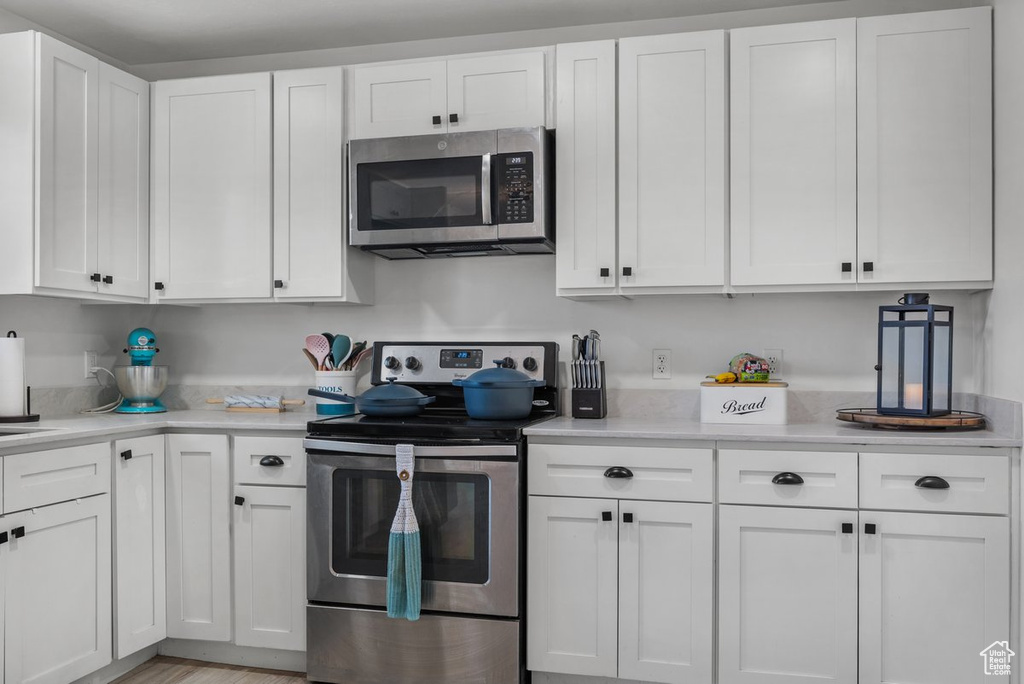 Kitchen with appliances with stainless steel finishes, white cabinetry, and light countertops