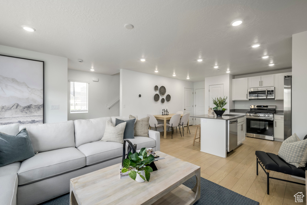 Living area with light wood-style floors, recessed lighting, and a textured ceiling