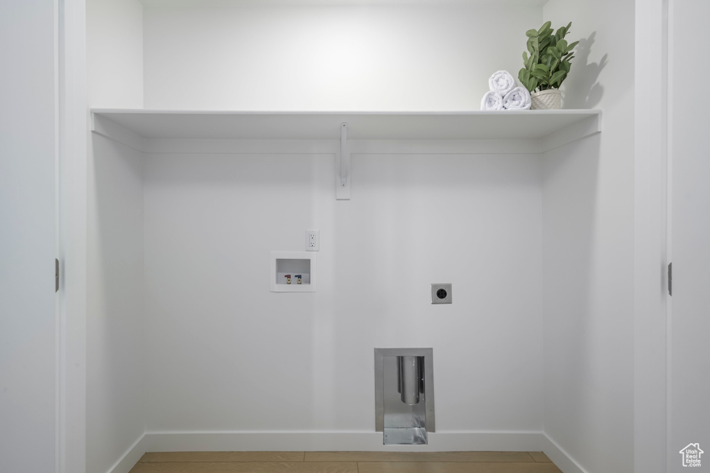 Laundry area with hookup for an electric dryer, hookup for a washing machine, and baseboards