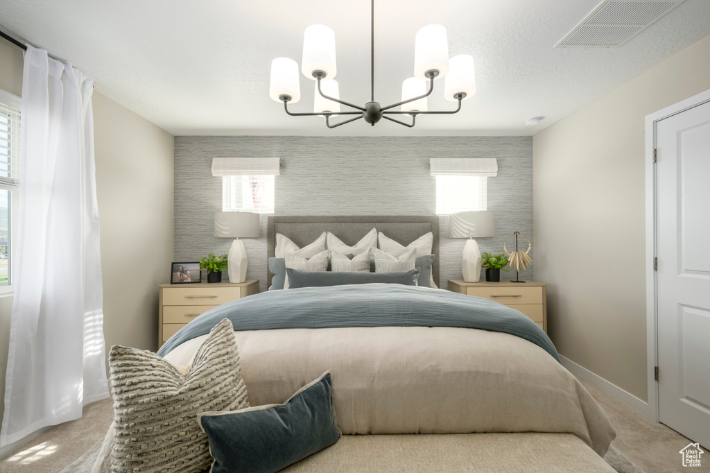 Carpeted bedroom with a chandelier, baseboards, and an accent wall
