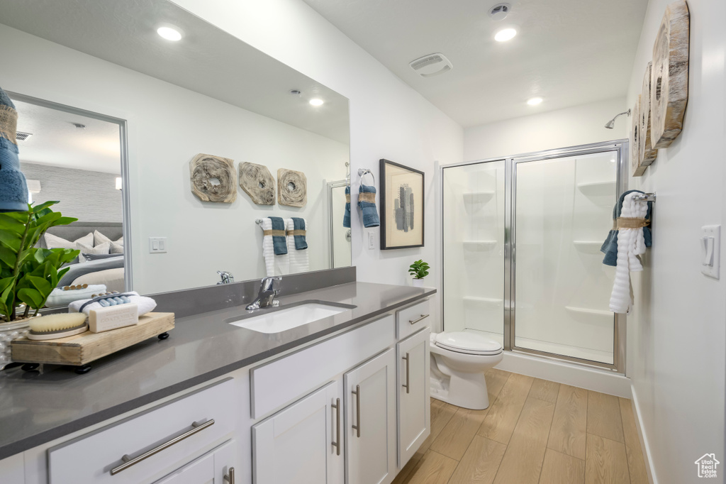 Full bathroom featuring vanity, a shower stall, toilet, wood finished floors, and recessed lighting