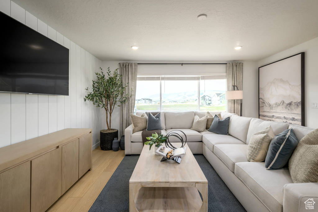 Living room with light wood-type flooring, recessed lighting, and a textured ceiling