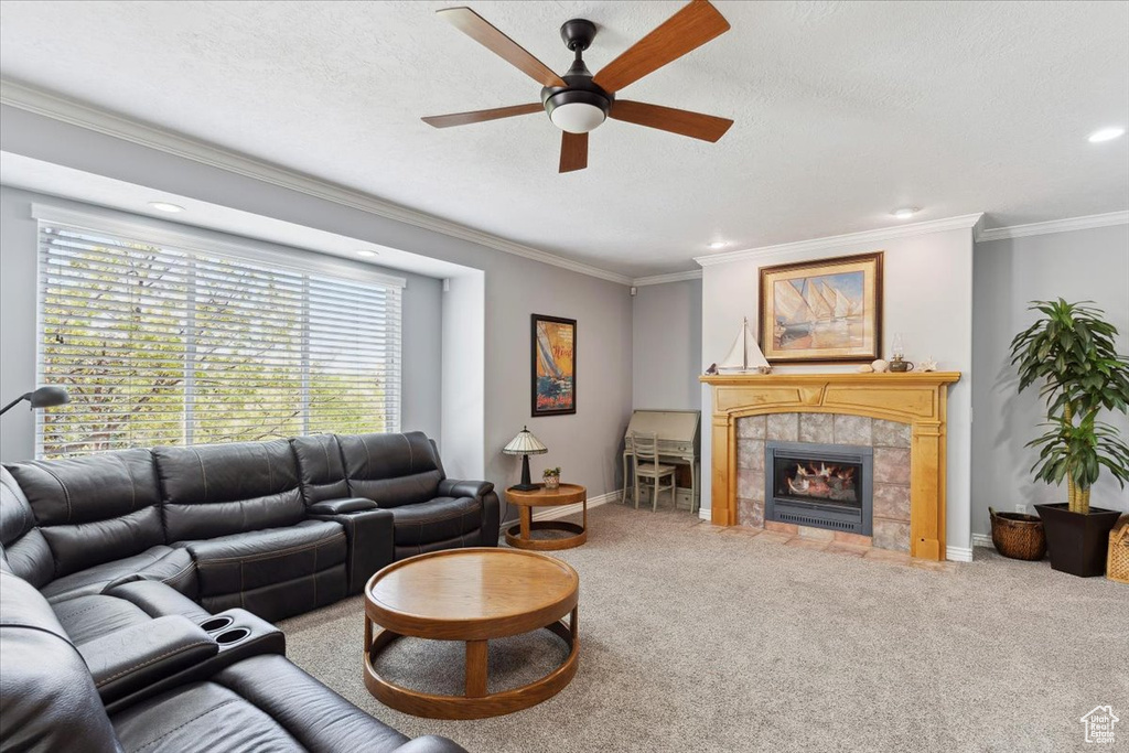 Carpeted living area with a ceiling fan, ornamental molding, baseboards, a tile fireplace, and recessed lighting
