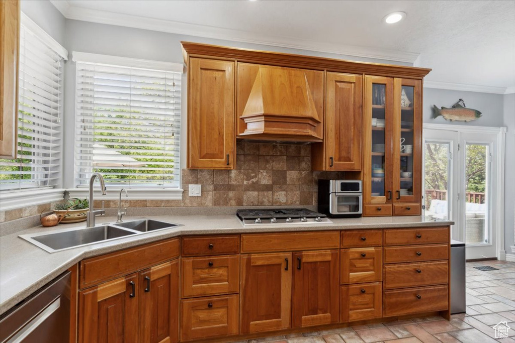 Kitchen featuring appliances with stainless steel finishes, custom exhaust hood, a sink, crown molding, and light countertops