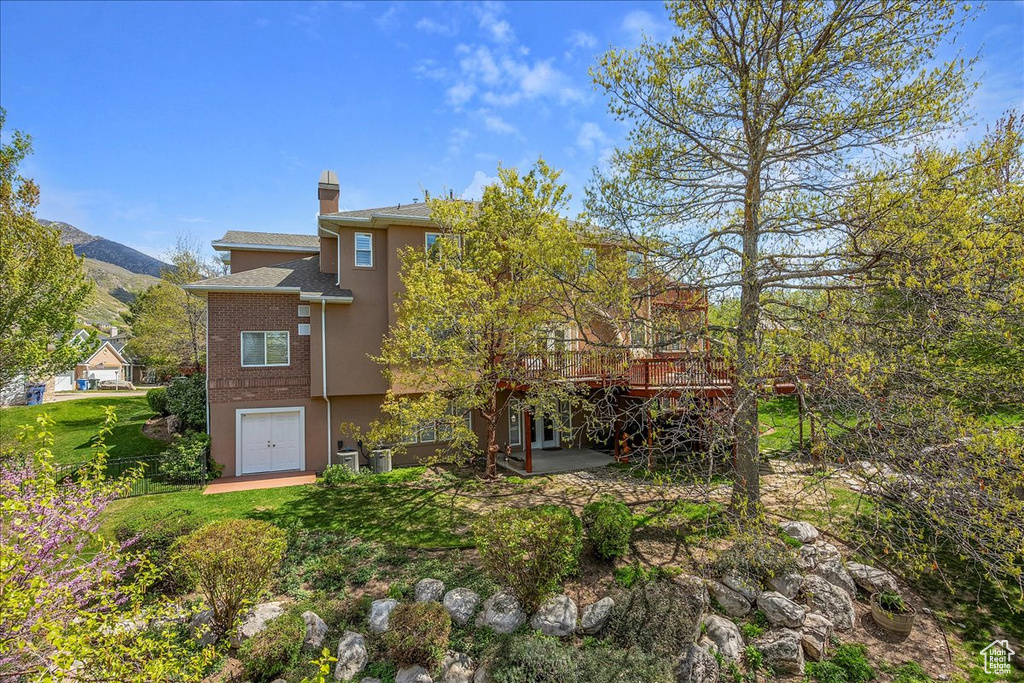 Rear view of house featuring a chimney, a patio, stucco siding, and a mountain view