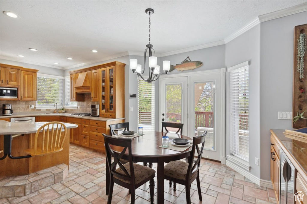 Dining space featuring a chandelier, ornamental molding, recessed lighting, beverage cooler, and stone tile floors