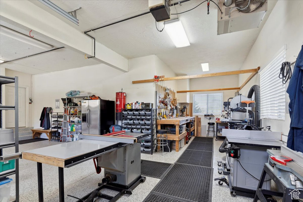 Garage featuring a workshop area, stainless steel fridge with ice dispenser, and a garage door opener