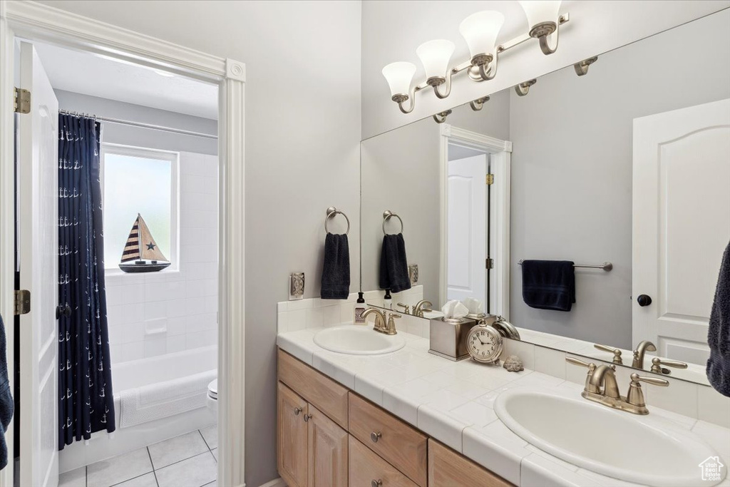 Bathroom featuring double vanity, toilet, shower / tub combo with curtain, and tile patterned floors
