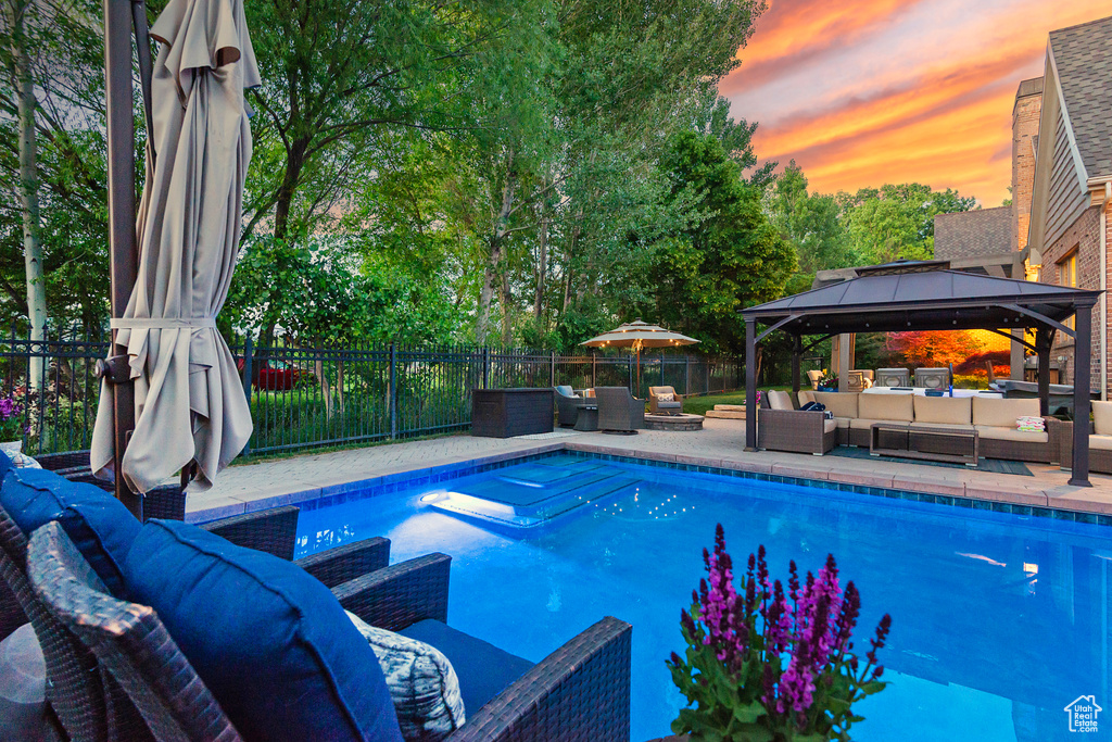View of pool featuring an outdoor hangout area, a gazebo, a fenced backyard, and a patio area