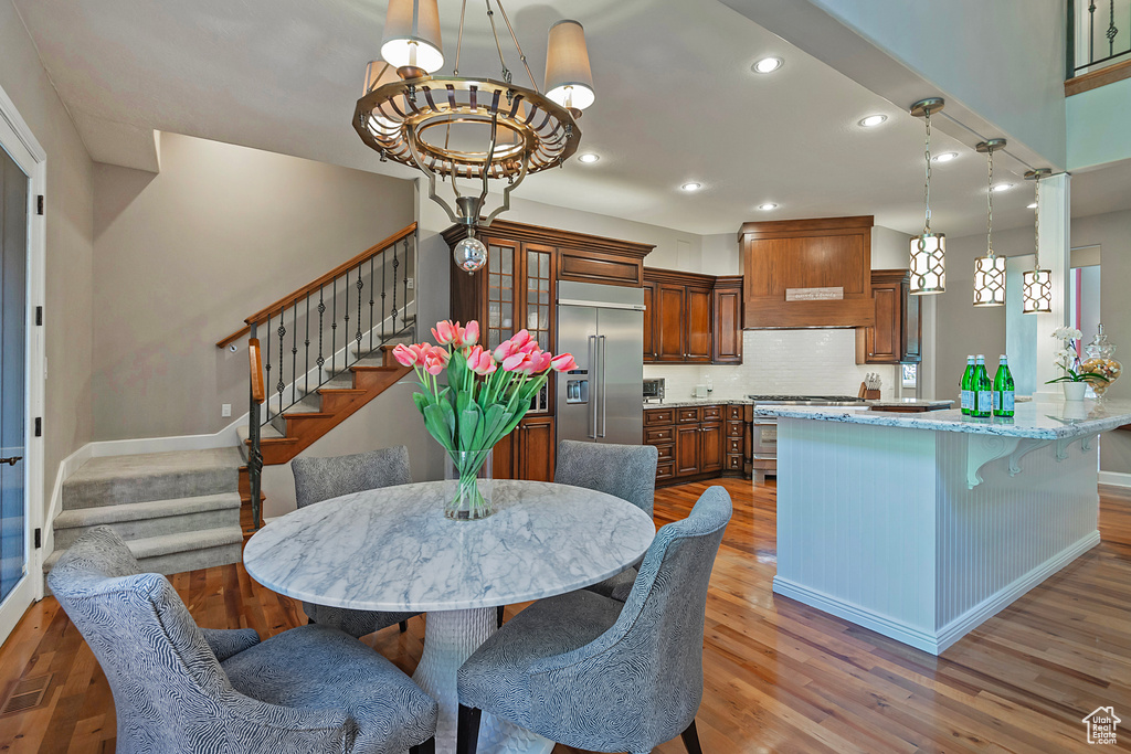 Dining area featuring wood finished floors, stairs, a chandelier, recessed lighting, and baseboards