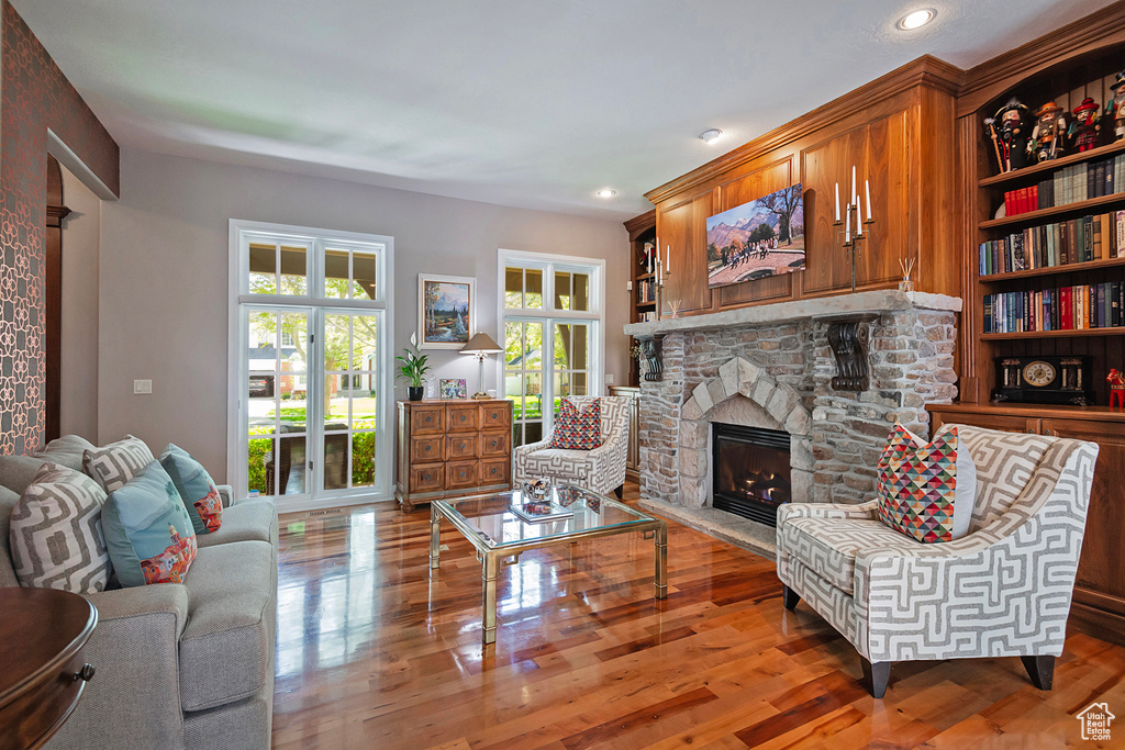 Living room with a stone fireplace, wood finished floors, and recessed lighting