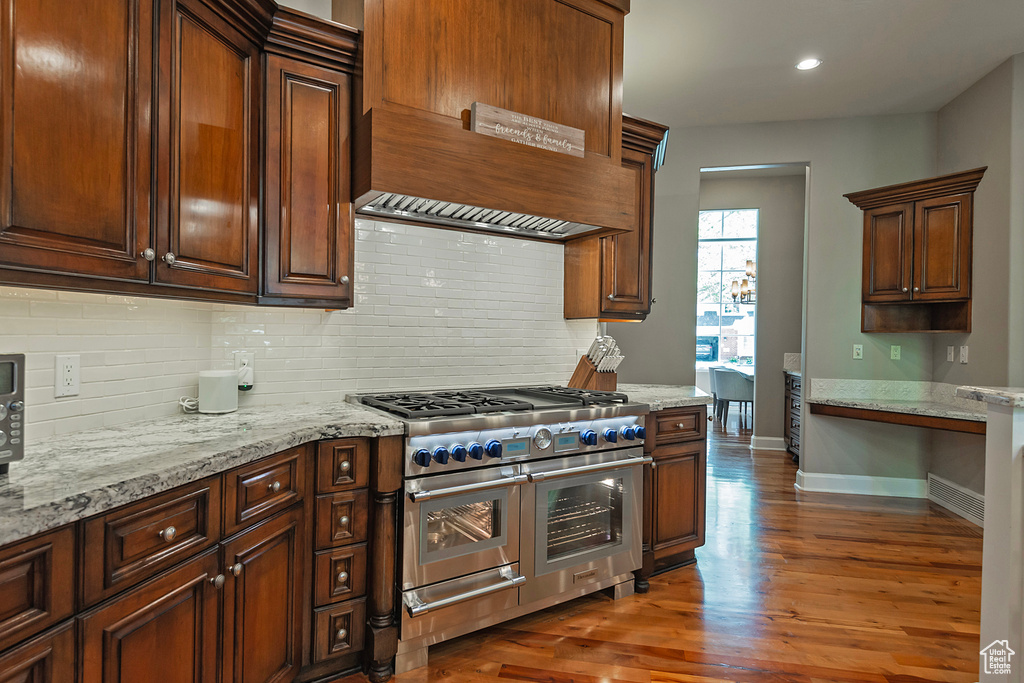 Kitchen with range with two ovens, custom range hood, backsplash, dark wood finished floors, and recessed lighting