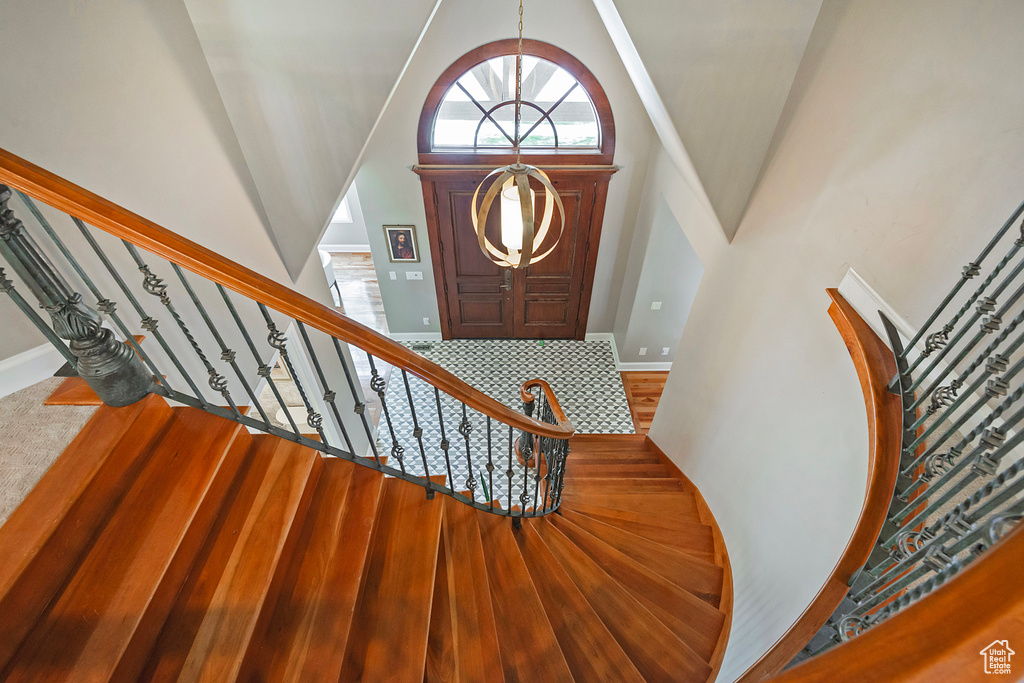Foyer with high vaulted ceiling, stairway, baseboards, and wood finished floors
