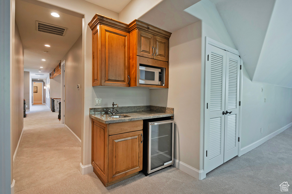 Indoor bar featuring wine cooler, light colored carpet, white microwave, baseboards, and recessed lighting