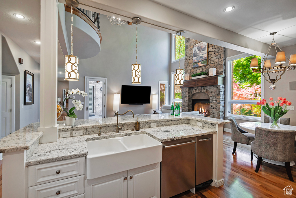 Kitchen featuring a sink, dishwasher, dark wood finished floors, open floor plan, and white cabinets