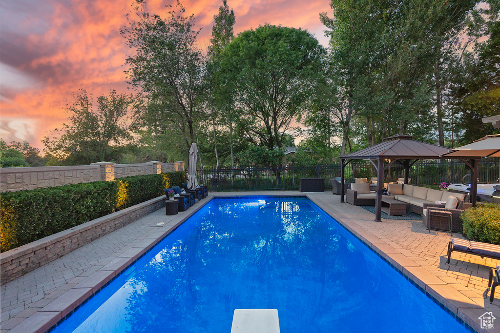 View of swimming pool with an outdoor living space, a gazebo, a fenced backyard, a patio, and view of wooded area